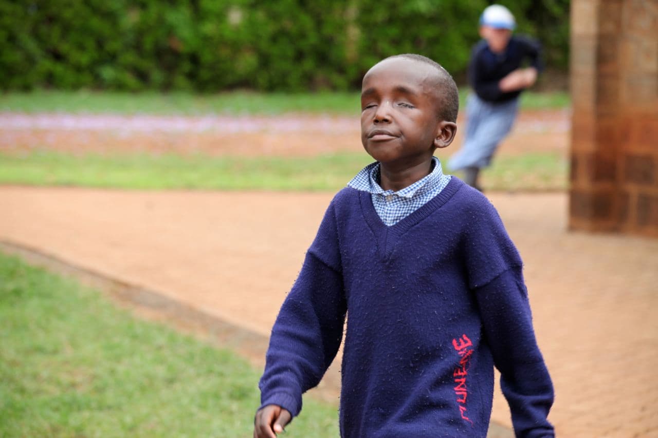 A blind boy in school uniform walking