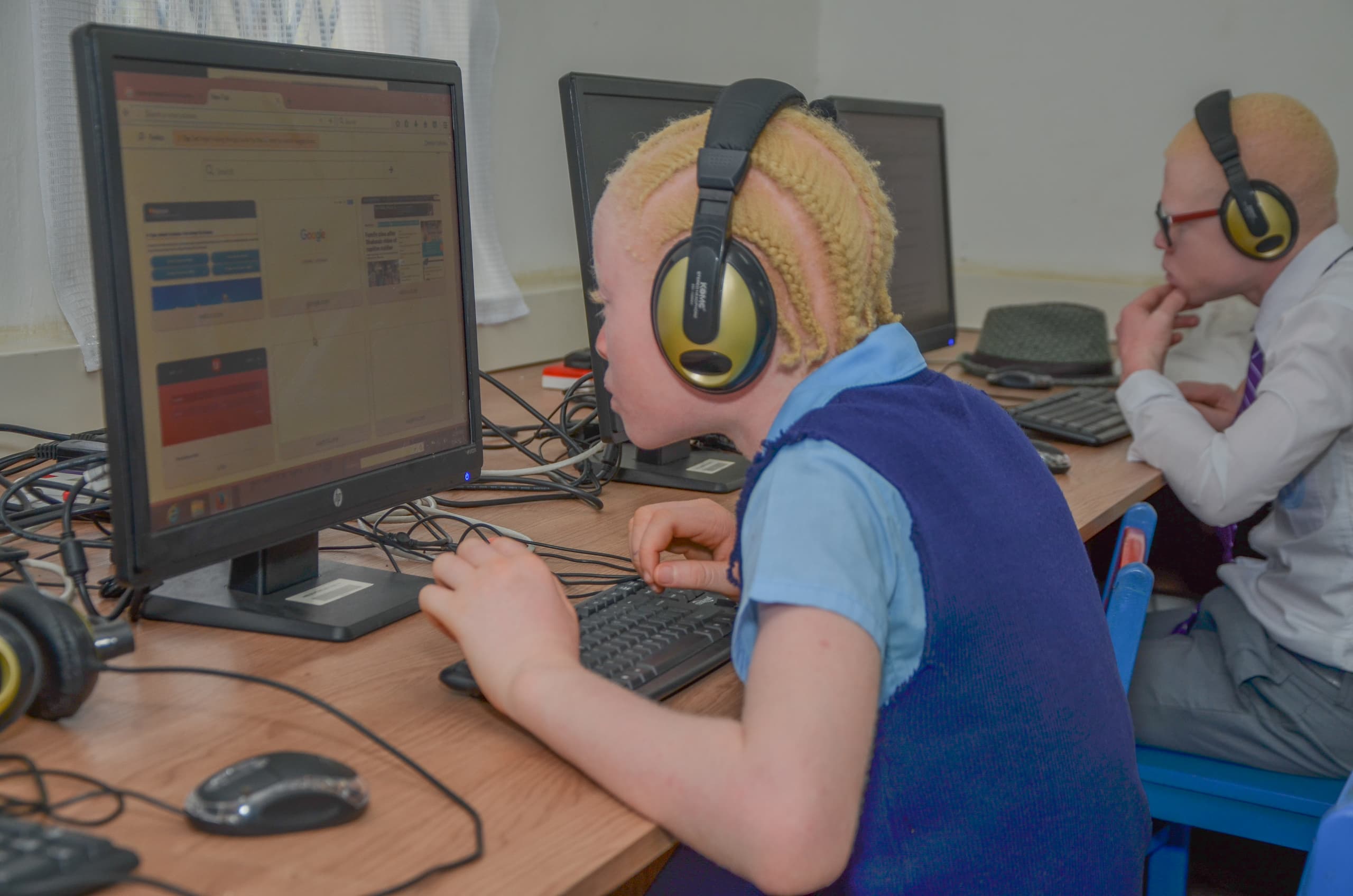 A student with albinism in uniform using a desktop computer